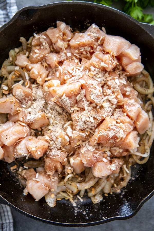 overhead shot of chicken in skillet with seasonings