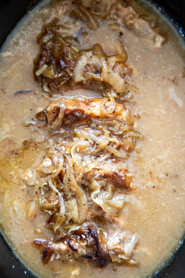 overhead shot of onions with gravy in crock pot