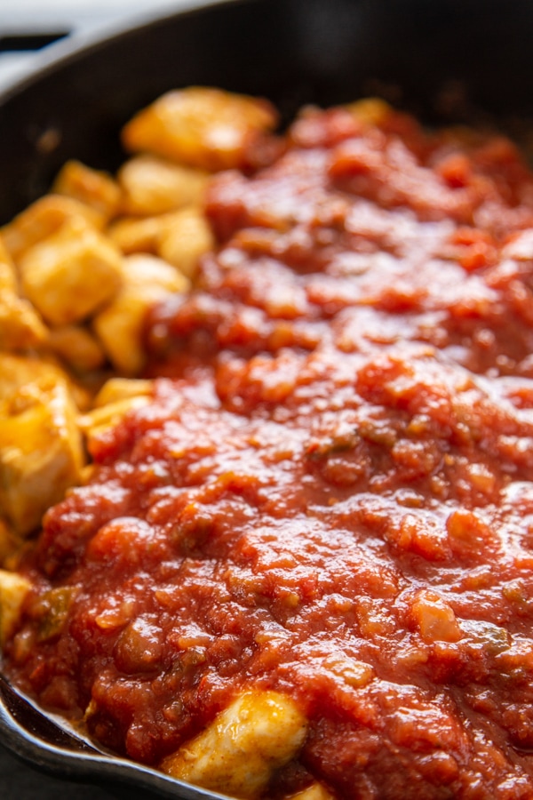 cooked chicken cubed in skillet with salsa over it