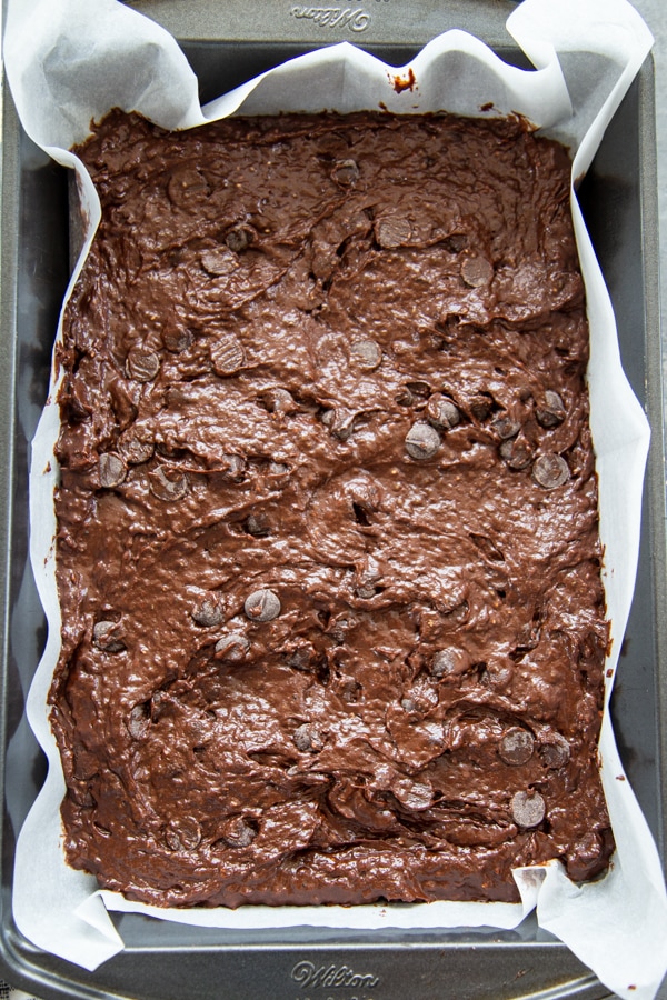 brownie batter in tin 9x13 pan lined with parchment paper