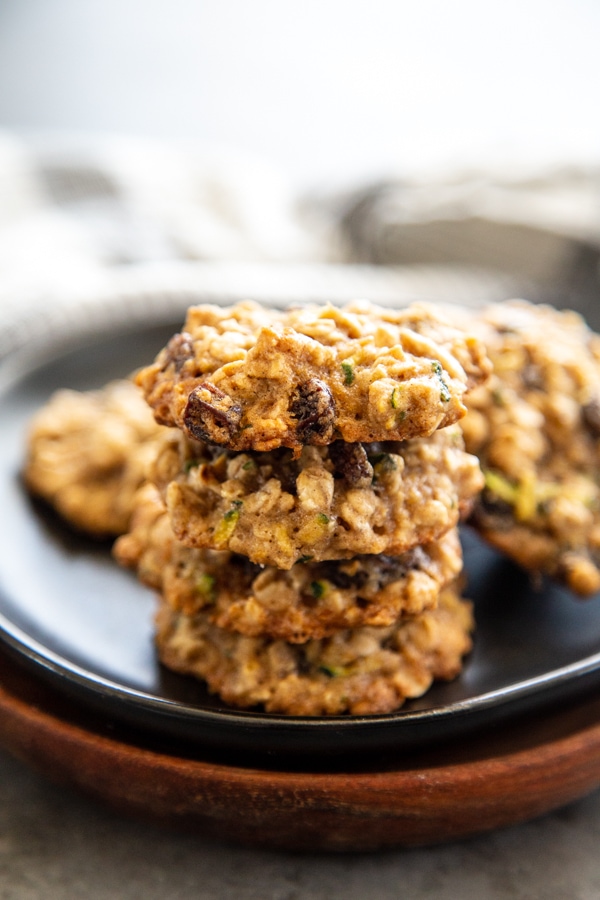 zucchini oatmeal raisin cookies staked on a black plate