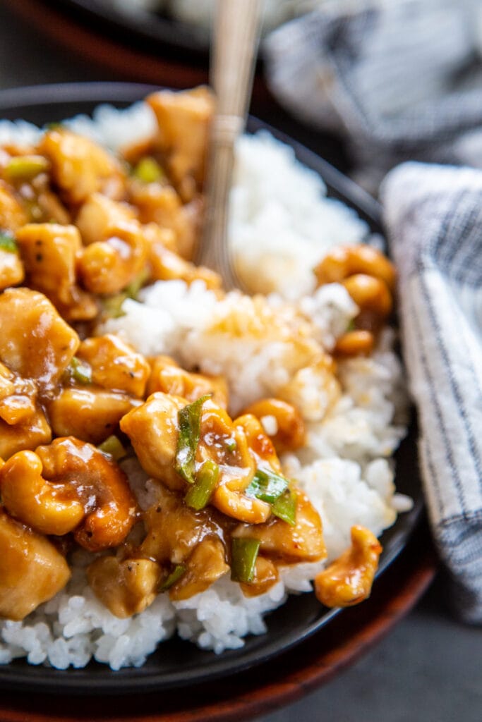 plate of cashew chicken over rice with fork close up shot
