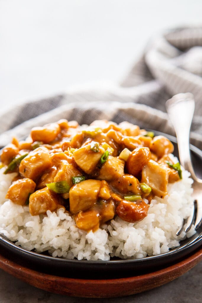 plate of cashew chicken over rice with fork