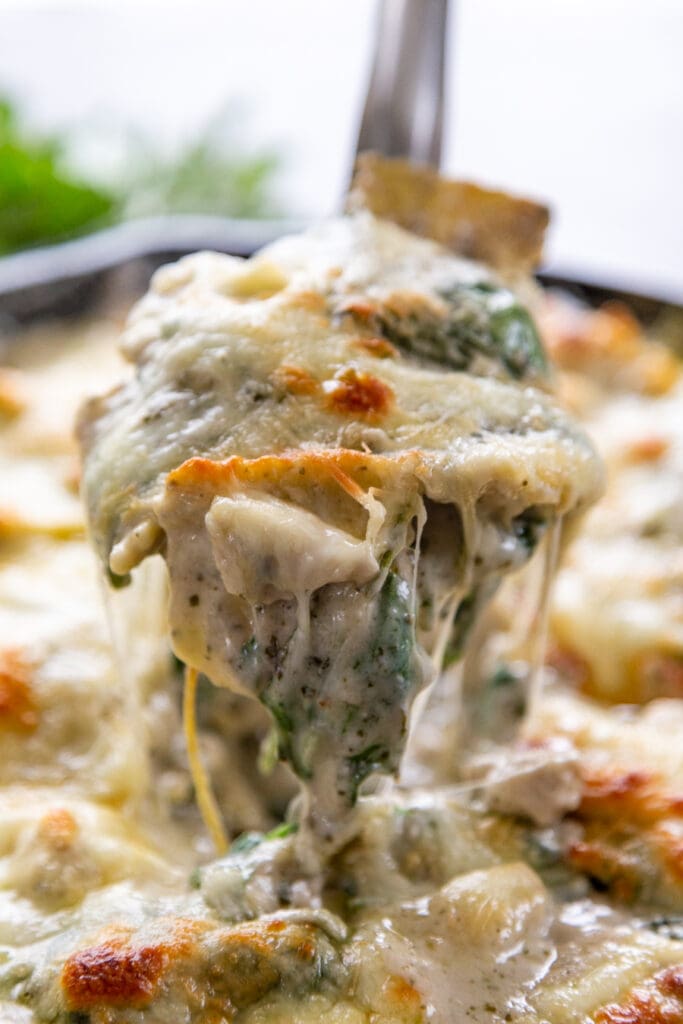 spoon and cheese pull from skillet with ravioli