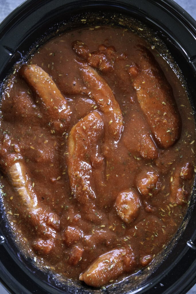overhead shot of italian sausages in sauce in slow cooker