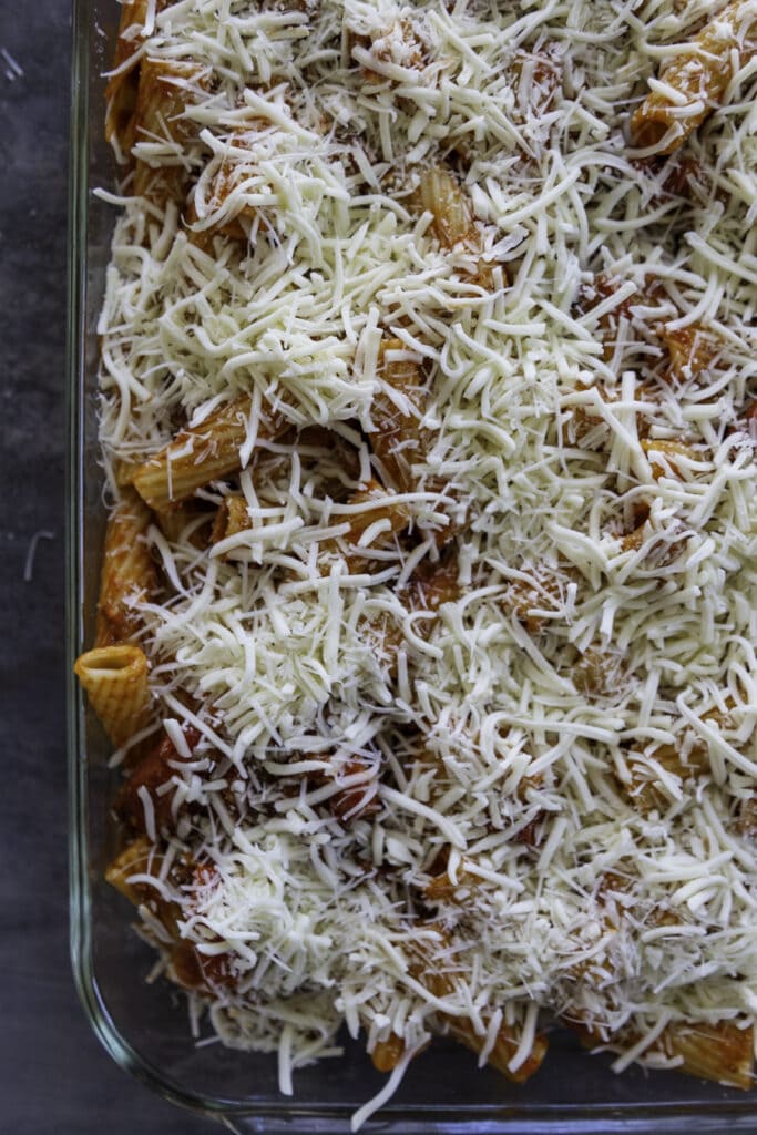 pasta in baking pan sprinkled with shredded cheese