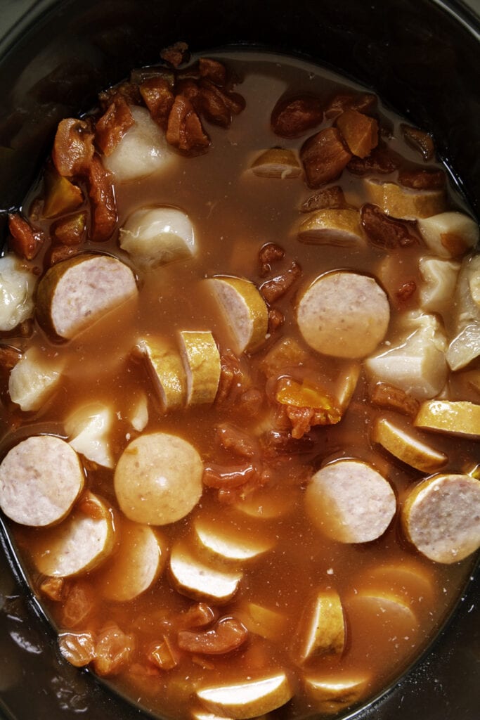 slow cooker with sausages, chicken and tomatoes