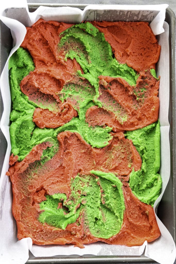 overhead shot of cookie dough both red and green in 9x13 baking pan spread
