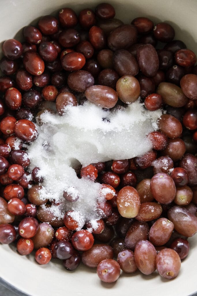 overhead shot of white pot with grapes, cranberries, sugar and water