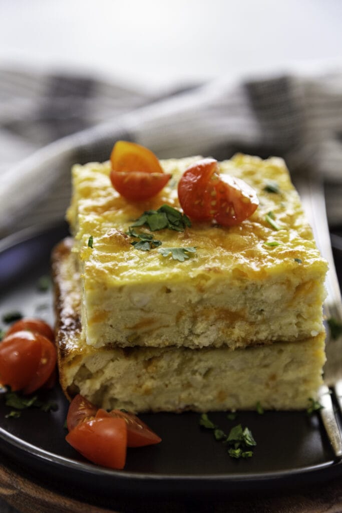 stack of slices of egg casserole on plate with tomatoes