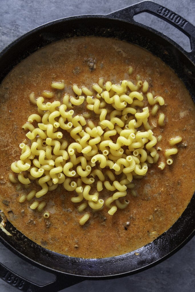 overhead shot of skillet with raw pasta and sauce