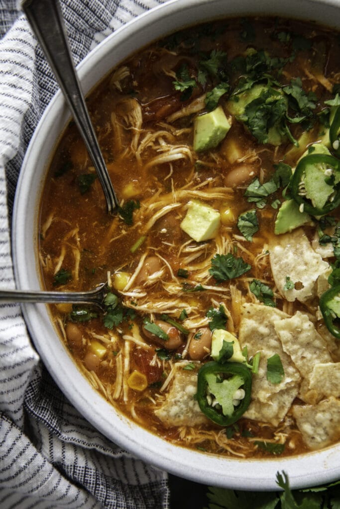 white bowl with soup and garnishes including tortilla chips