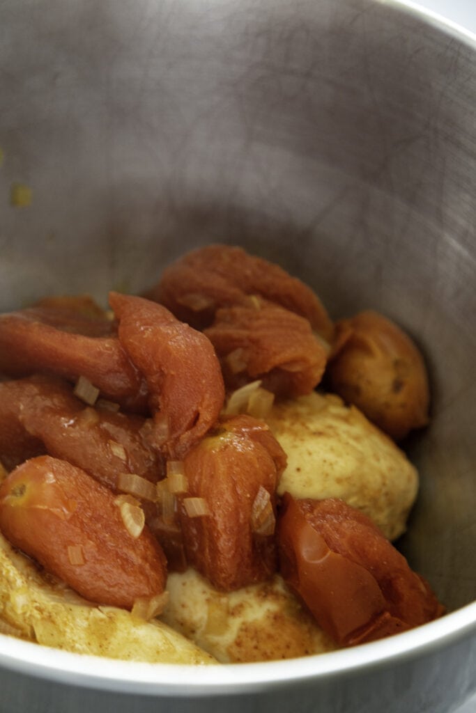 cooked chicken and tomatoes in mixing bowl