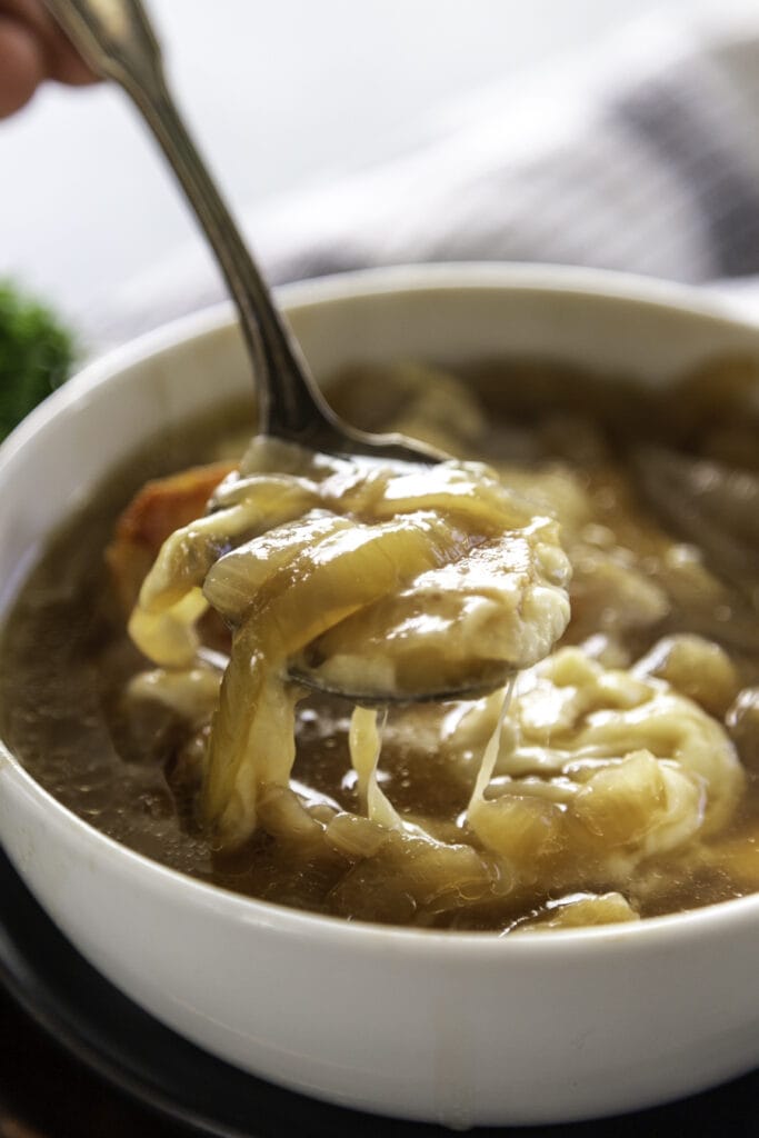 spoon of french onion soup with cheese pull