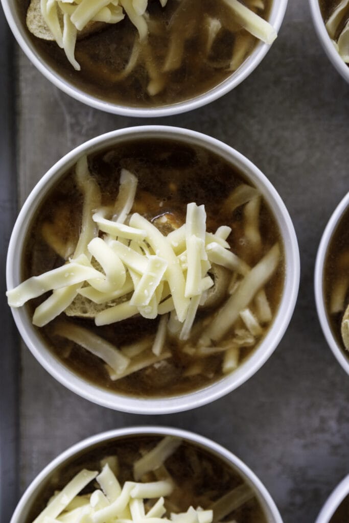 small bowls with onion soup and piece of bread and shredded cheese on top
