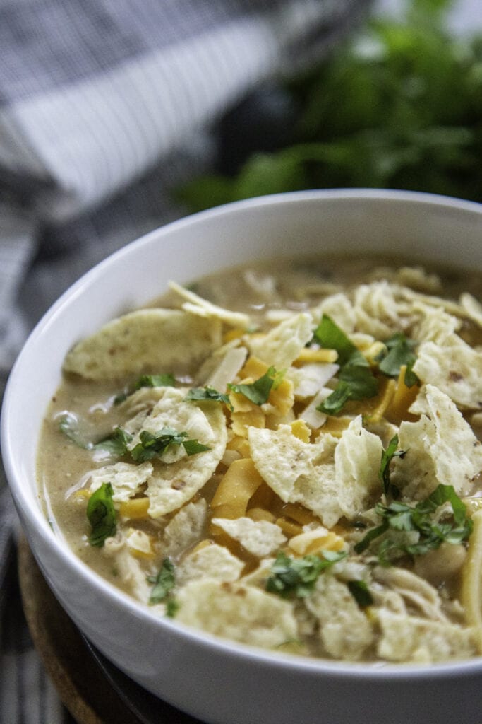 side view with chips and cilantro over bowl of white chicken chili