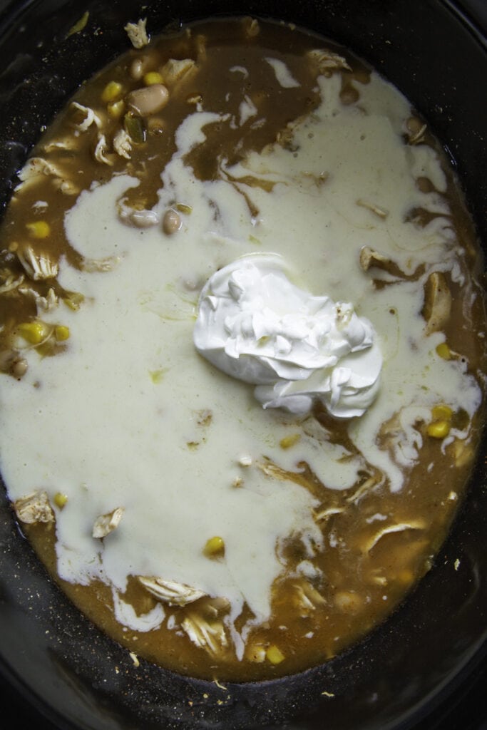 cream and sour cream in slow cooker broth with chicken