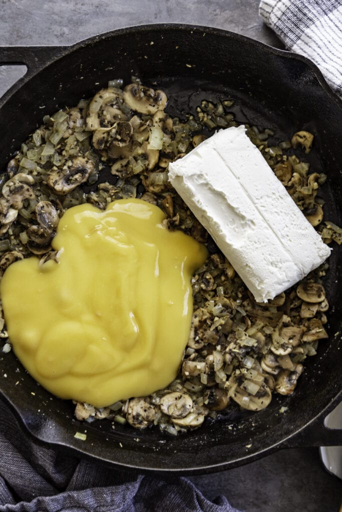 skillet with cooked mushrooms onions cream cheese and cream of chicken
