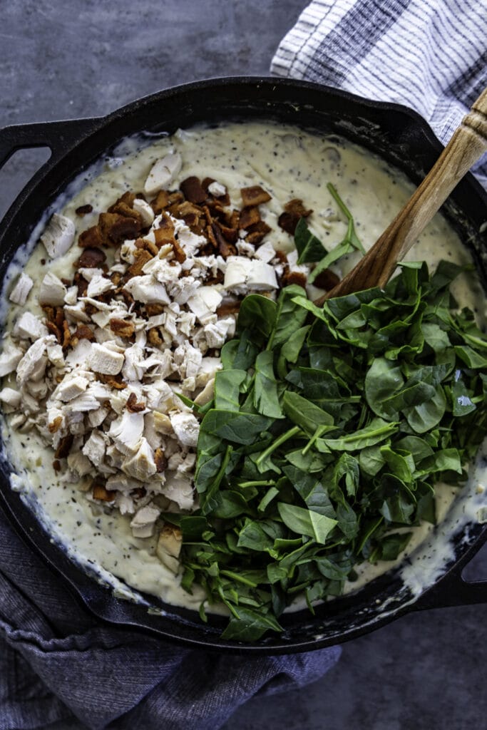 overhead shot of skillet with chicken, bacon and spinach and creamy sauce