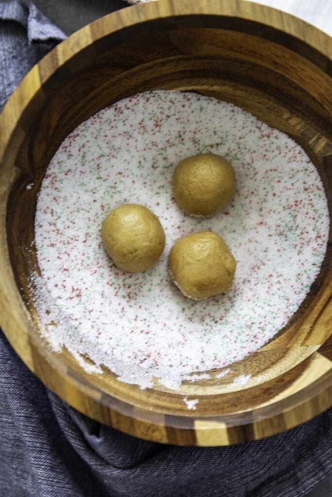 cookie dough balls in a bowl of sugar