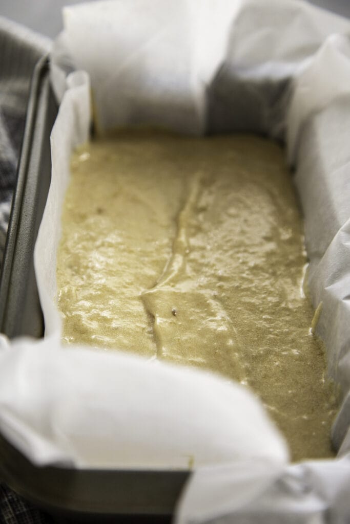 banana bread batter in bread pan with parchment paper