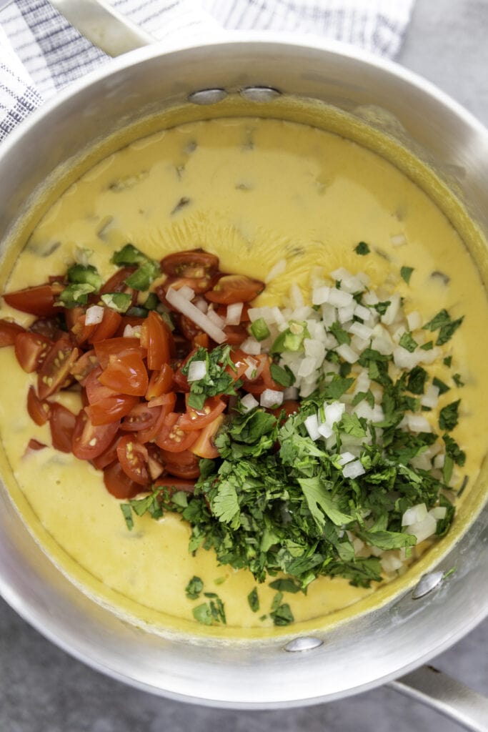 overhead shot queso in pan with fresh cilantro onion and tomatoes