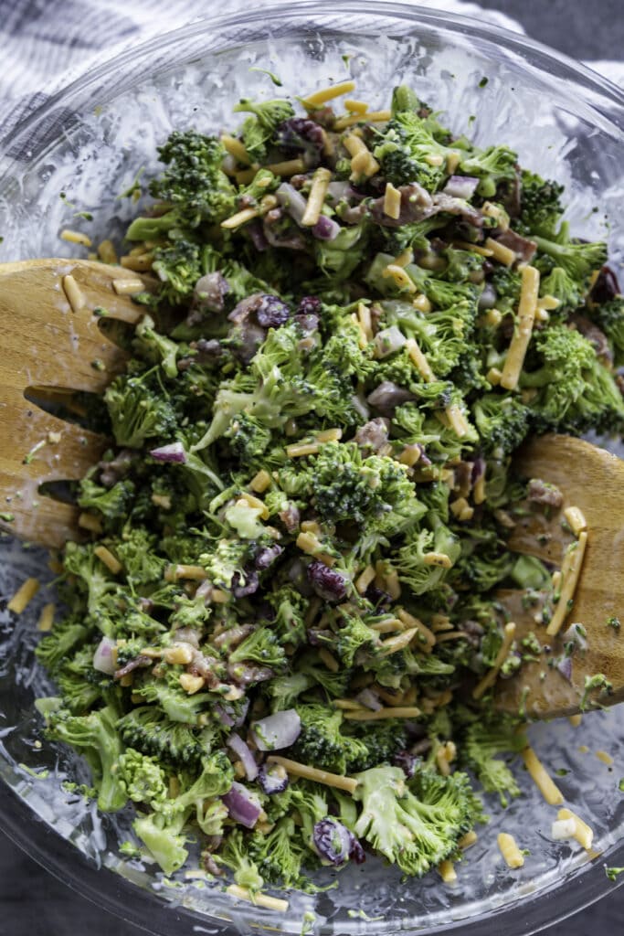 overhead shot glass bowl broccoli salad with wooden tongs