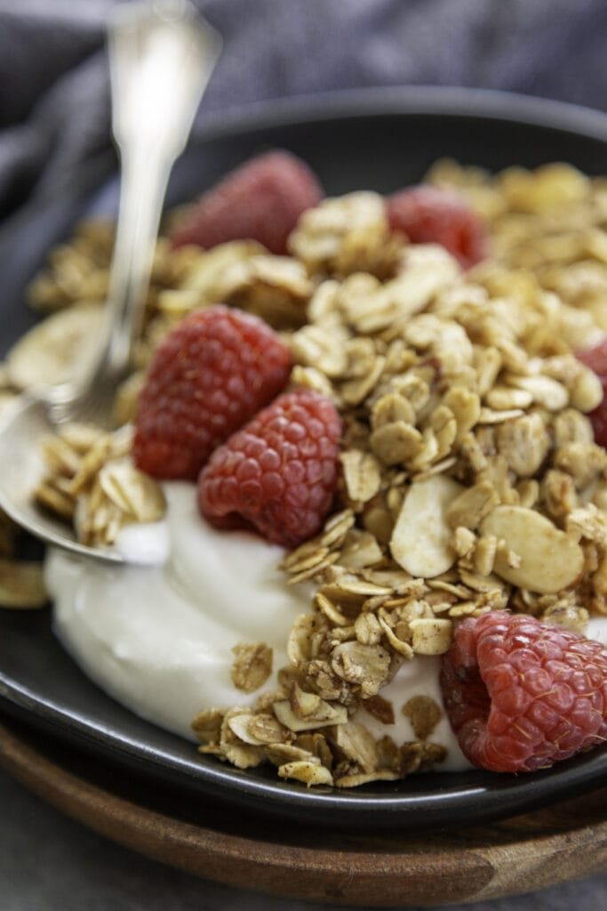 black plate with yogurt, rapberries and granola