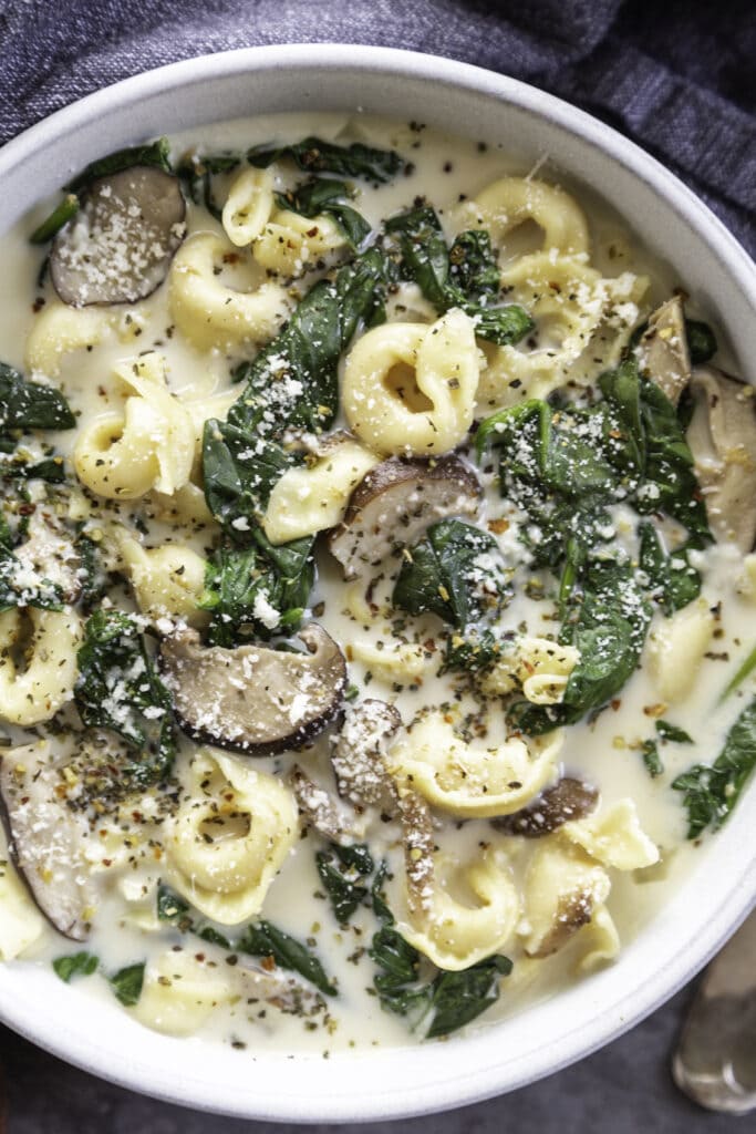 overhead shot bowl of creamy tortellini soup with spoon