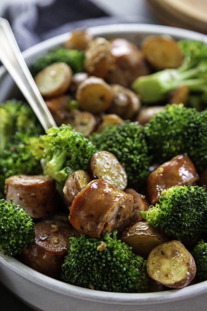 broccoli, potatoes and sausage in a bowl with fork