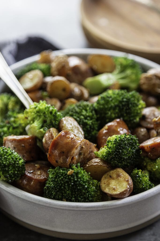 broccoli, potatoes and sausage in a bowl with fork