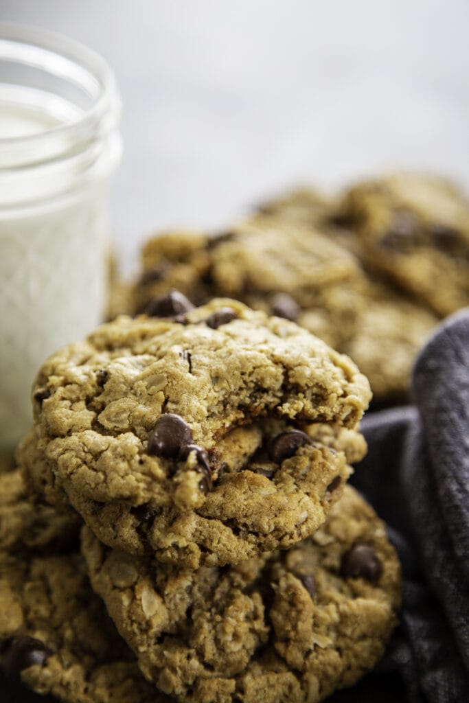 stack of chocolate chip peanut butter cookies with milk with bite taken out of cookie