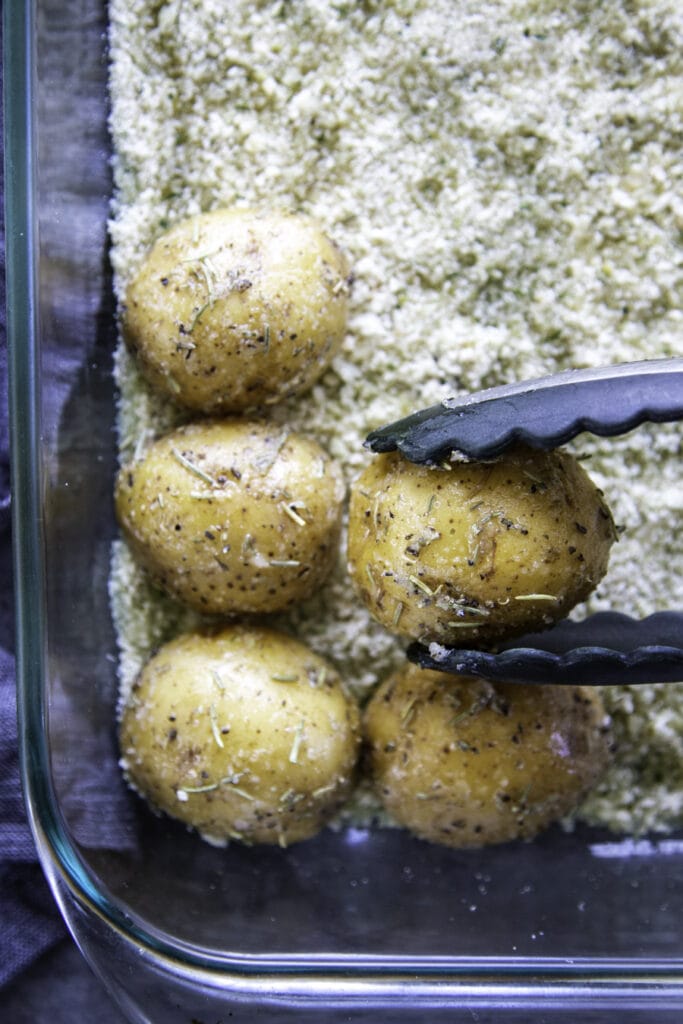 placing potatoes in baking pan with bread crumbs