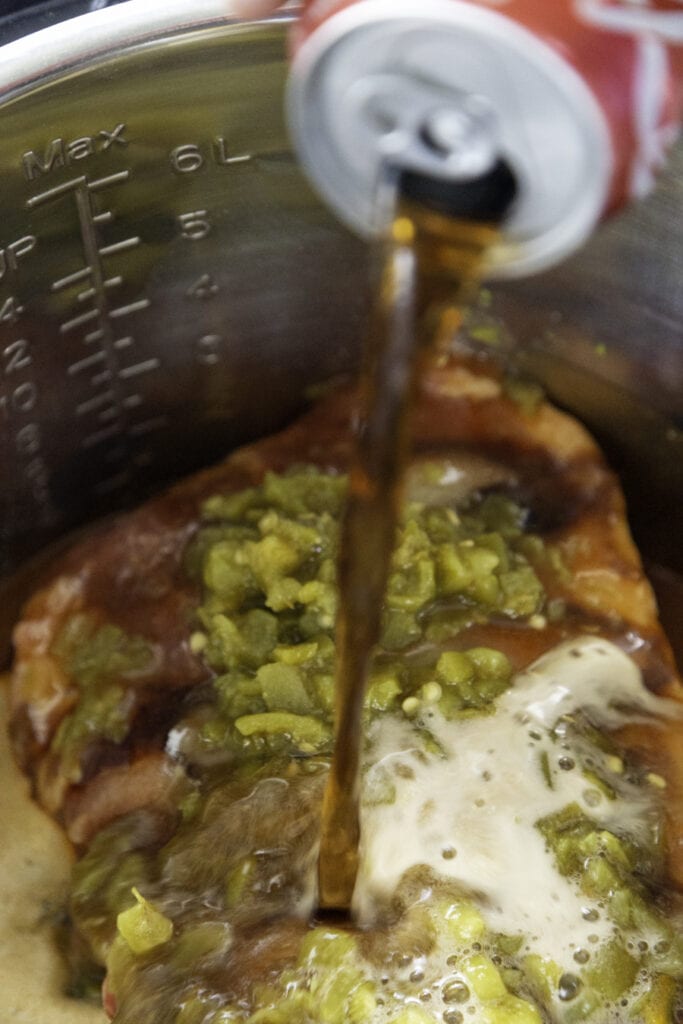 pork in instant pot with coke being poured over it