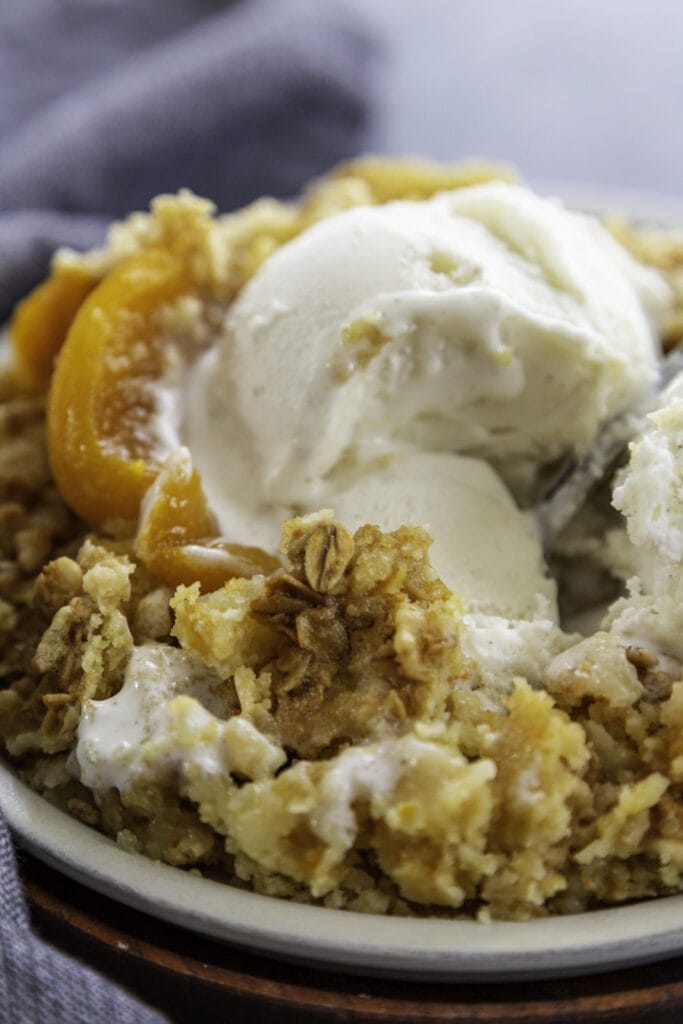 close up shot peach dump cake with ice cream