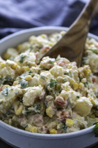 southwest potato salad in serving bowl with wooden spoon
