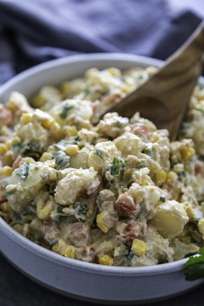 shot of potato salad in bowl with wooden serving spoon