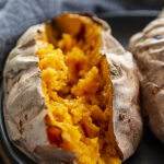 half of baked sweet potato on black plate with nothing on the potato