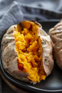 half of baked sweet potato on black plate with nothing on the potato