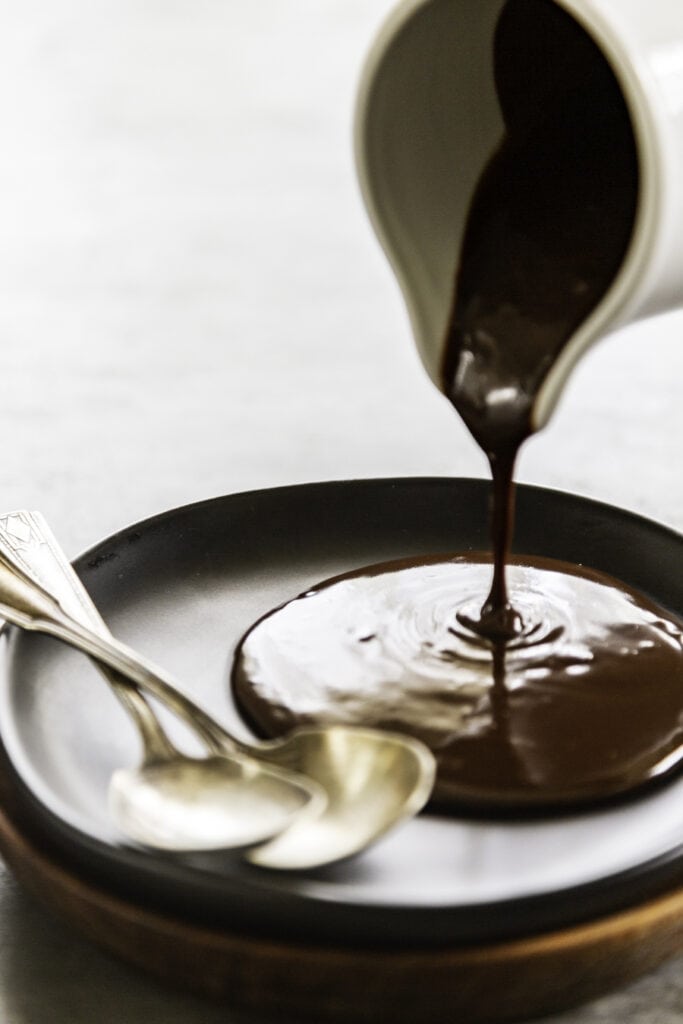 pouring hot fudge on to a plate with spoons