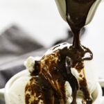 peanut butter hot fudge poured over ice cream in white bowl