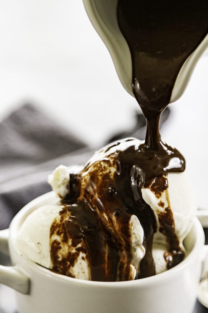 peanut butter hot fudge poured over ice cream in white bowl