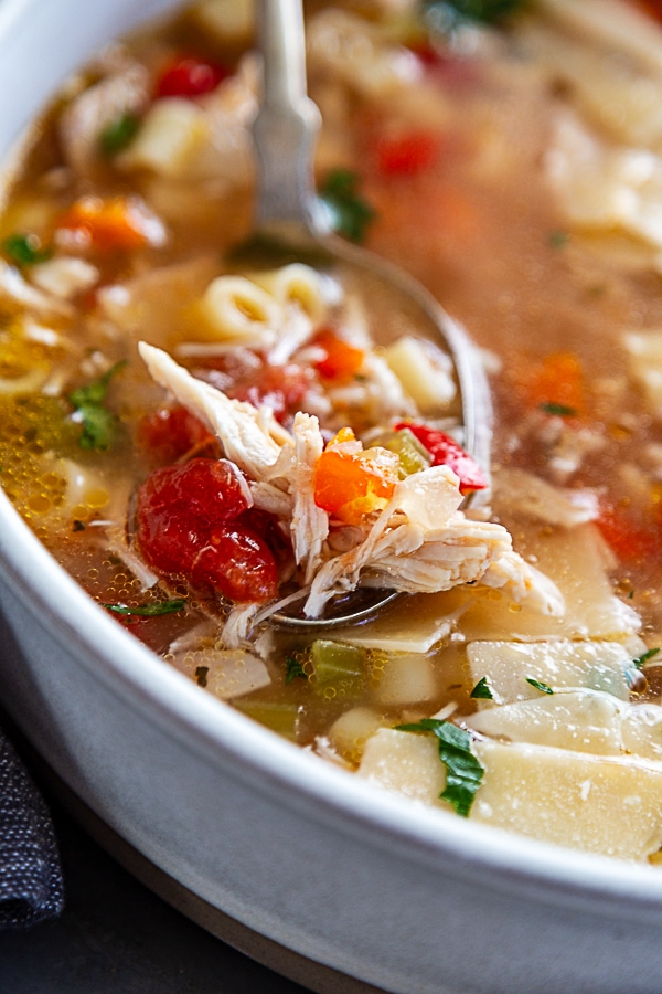 siclian chicken soup in white bowl with soup spoon, full of soup