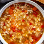 overhead shot of siclian chicken soup in white bowl with french bread on the side