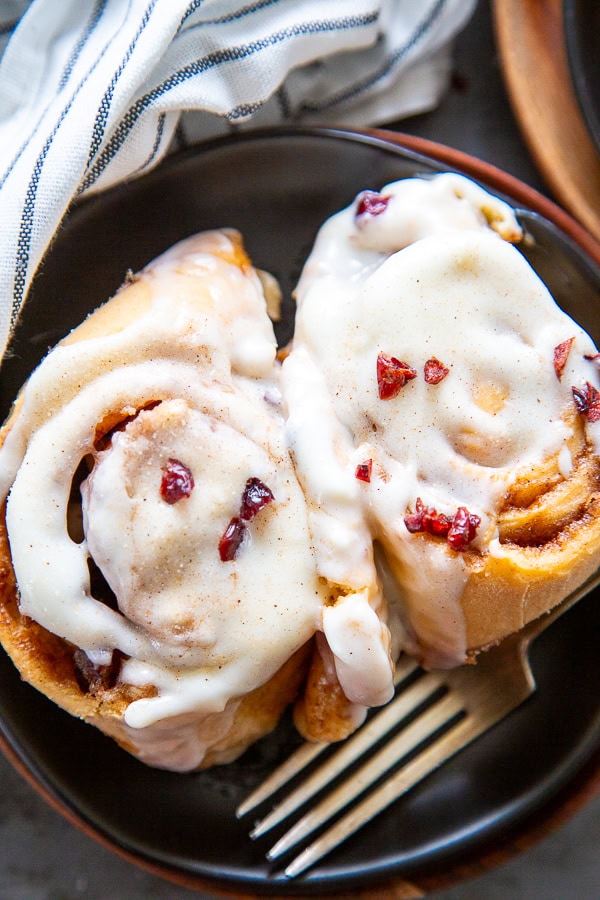 overhead shot of cranberry cinnamon rolls two on a black plate