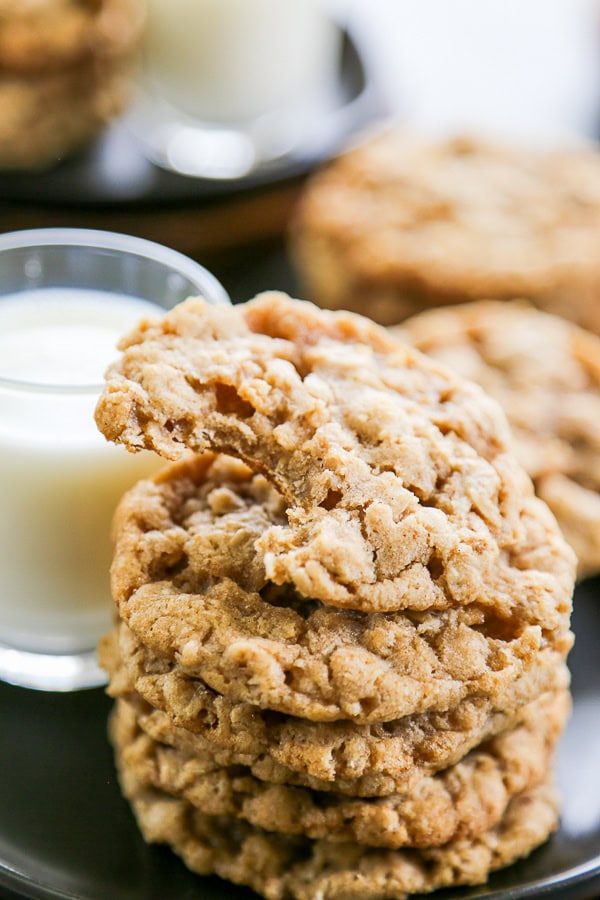 stack of oatmeal cookies with bite out of one and glass of milk